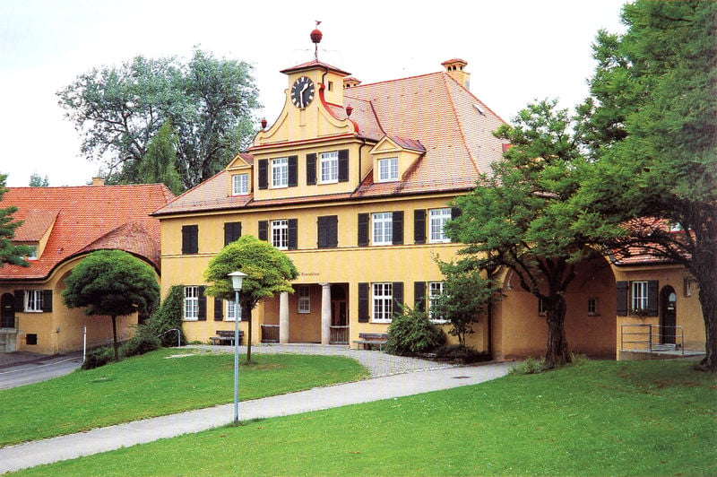 Altenhof der Siedlung Gmindersdorf. by Theodor Fischer. 1903–1915. Motifs recorded: uhr, haus, bäume, rasen, dach, laterne, gelb, säulen.