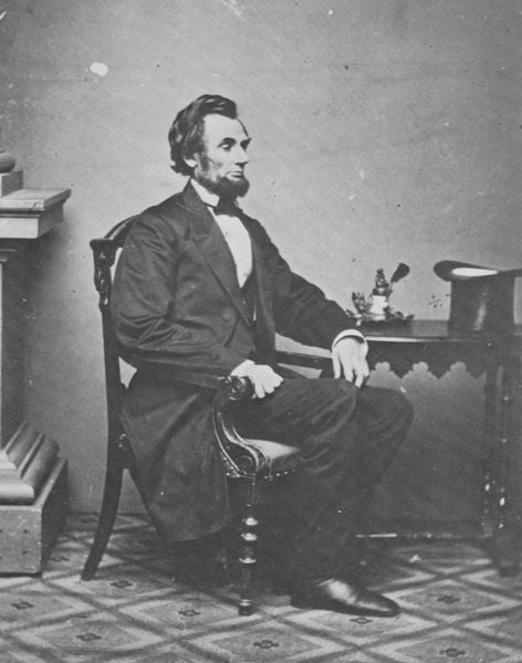 Abraham Lincoln. by Mathew B. Brady. 1861. Motifs recorded: stuhl, tisch, bart, mann, zylinder, lincoln, foto, sitzen.